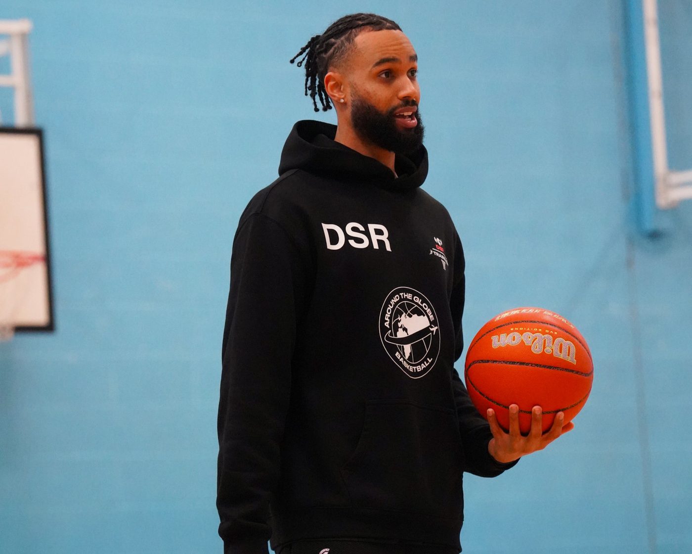 Coach Dom Scott-Robinson holding a basketball